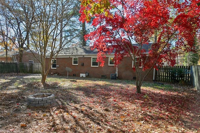 back of house with a fire pit, crawl space, central air condition unit, and a fenced backyard