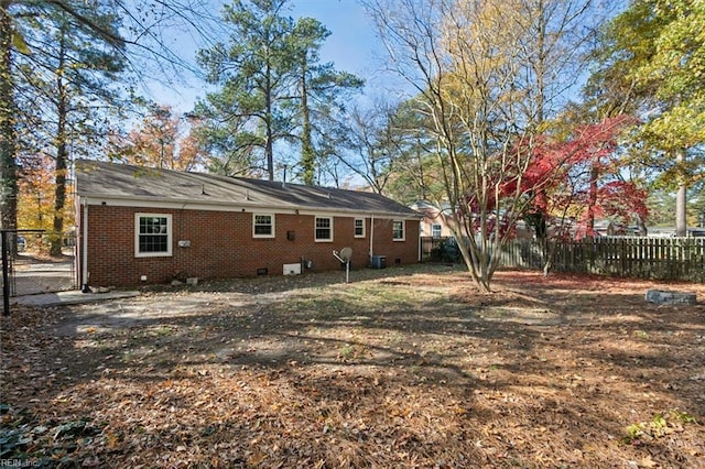 back of house featuring a fenced backyard, a gate, and brick siding