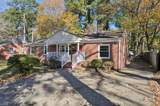 bungalow-style house featuring brick siding, covered porch, and fence
