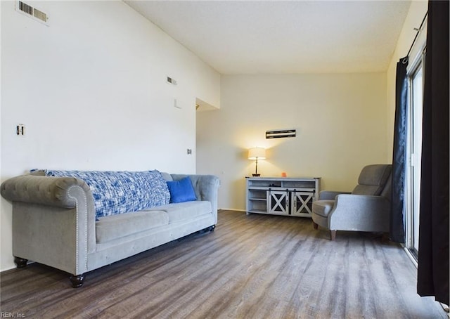 living room featuring wood finished floors, visible vents, vaulted ceiling, and baseboards