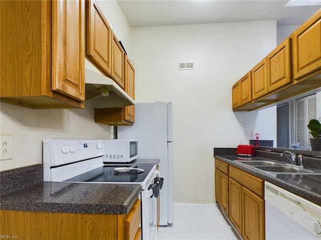 kitchen featuring white appliances, brown cabinetry, under cabinet range hood, a sink, and visible vents