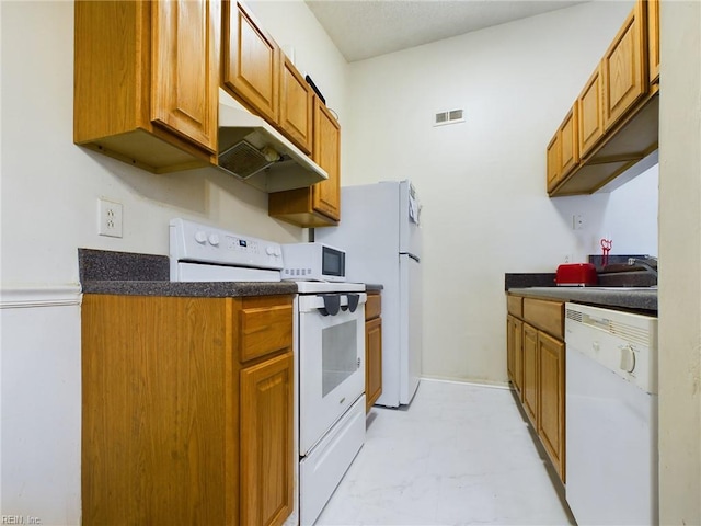 kitchen with white appliances, brown cabinetry, under cabinet range hood, dark countertops, and visible vents