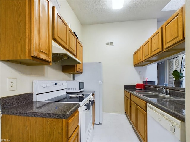 kitchen with a sink, under cabinet range hood, visible vents, white appliances, and a textured ceiling