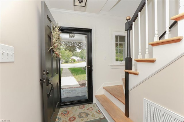 doorway featuring baseboards, ornamental molding, stairs, and visible vents