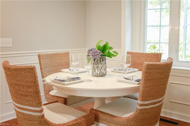 dining space with a decorative wall, wood finished floors, and visible vents