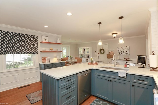 kitchen with a peninsula, stainless steel dishwasher, a sink, and light wood-style floors