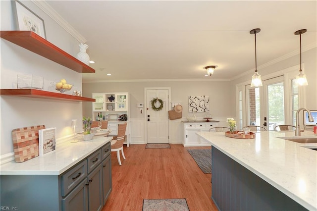 kitchen with open shelves, decorative light fixtures, crown molding, and a sink