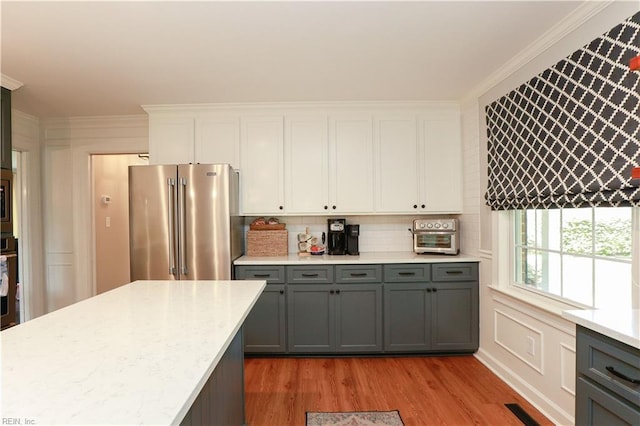 kitchen with tasteful backsplash, appliances with stainless steel finishes, light wood finished floors, white cabinetry, and gray cabinetry