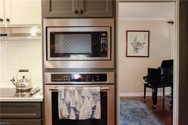 kitchen with baseboards, wood finished floors, appliances with stainless steel finishes, light countertops, and ornamental molding