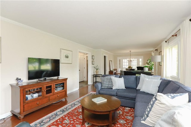 living area featuring a chandelier, wood finished floors, crown molding, and baseboards