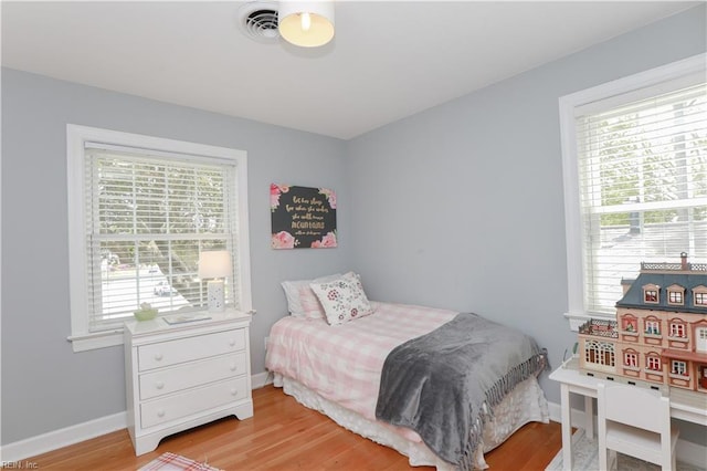bedroom featuring light wood-type flooring, visible vents, baseboards, and multiple windows