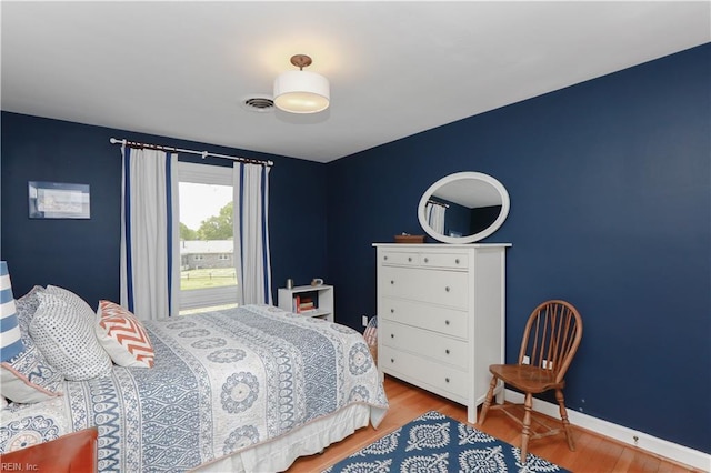 bedroom with wood finished floors, visible vents, and baseboards