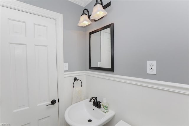 half bathroom featuring wainscoting and a sink