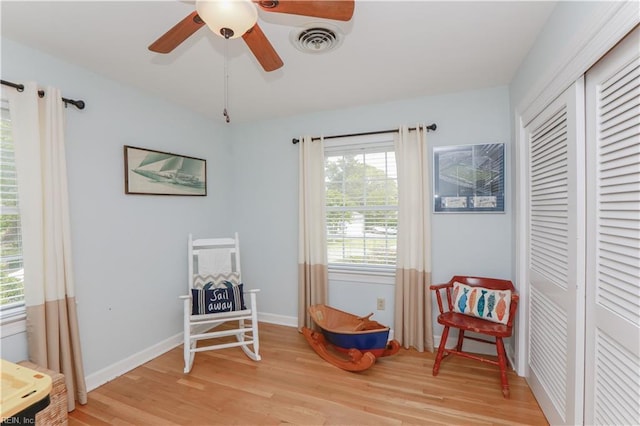 sitting room featuring light wood-type flooring, baseboards, a ceiling fan, and visible vents