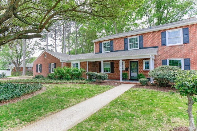 traditional-style house featuring brick siding, a porch, and a front yard