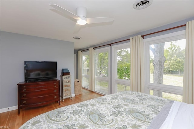 bedroom with ceiling fan, baseboards, wood finished floors, and visible vents