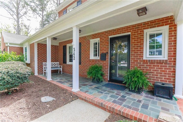 property entrance with a porch and brick siding