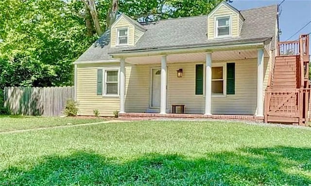 cape cod-style house with covered porch, a shingled roof, a front yard, and fence
