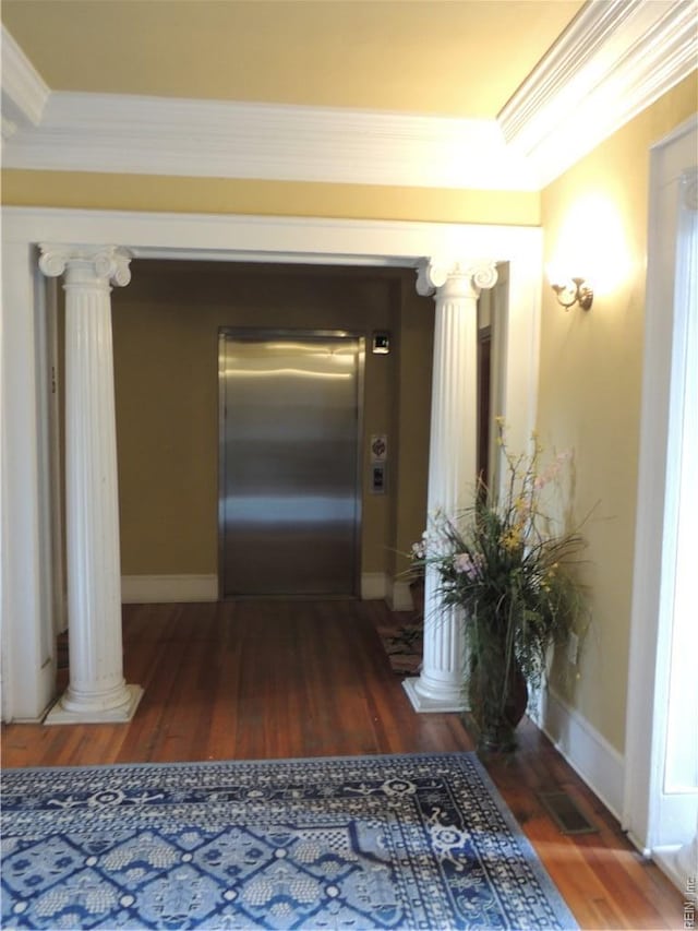 hallway with wood finished floors, baseboards, decorative columns, and elevator