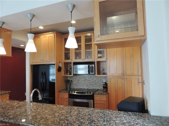 kitchen featuring dark stone countertops, stainless steel range with electric cooktop, glass insert cabinets, backsplash, and freestanding refrigerator
