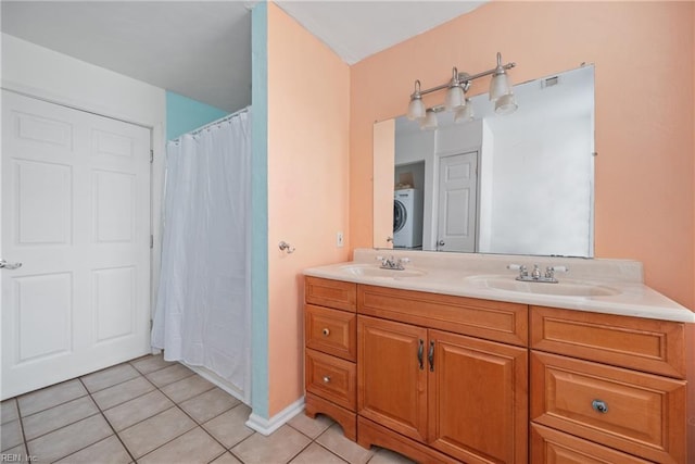 full bathroom with double vanity, stacked washer and dryer, tile patterned flooring, and a sink