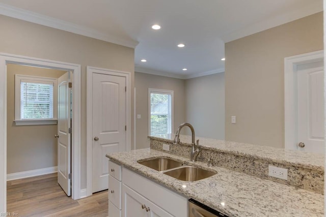 kitchen featuring white cabinets, a sink, light wood-type flooring, light stone counters, and ornamental molding