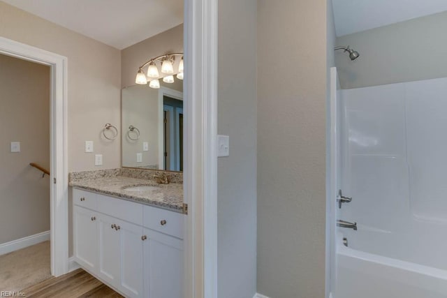 full bath with baseboards, vanity, and  shower combination