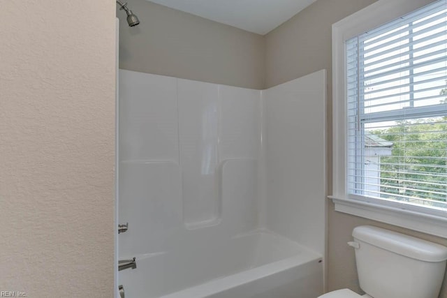 bathroom with shower / bath combination, a textured wall, and toilet