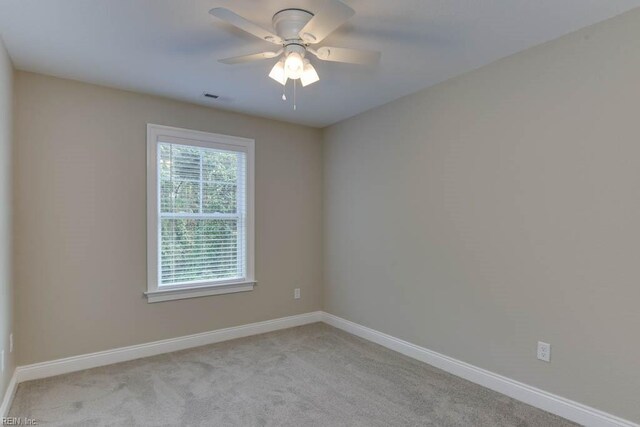 empty room with carpet floors, visible vents, baseboards, and ceiling fan