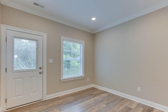 entryway with baseboards, ornamental molding, light wood finished floors, and visible vents