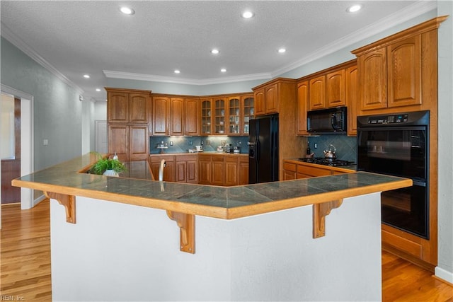 kitchen with brown cabinets, black appliances, and a breakfast bar