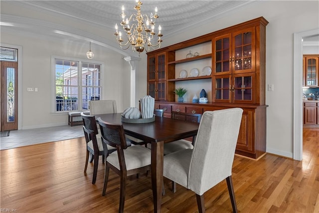 dining space with an inviting chandelier, light wood-style flooring, and crown molding