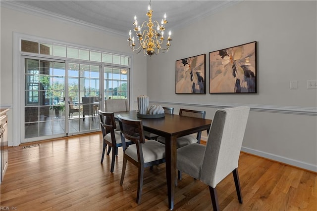 dining space featuring an inviting chandelier, baseboards, ornamental molding, and light wood-style flooring