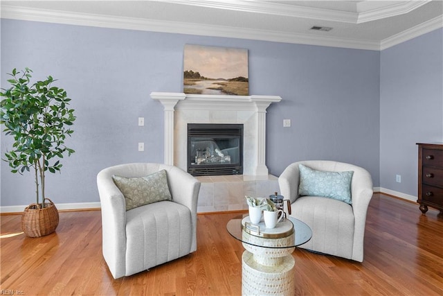 sitting room featuring a fireplace, baseboards, wood finished floors, visible vents, and ornamental molding