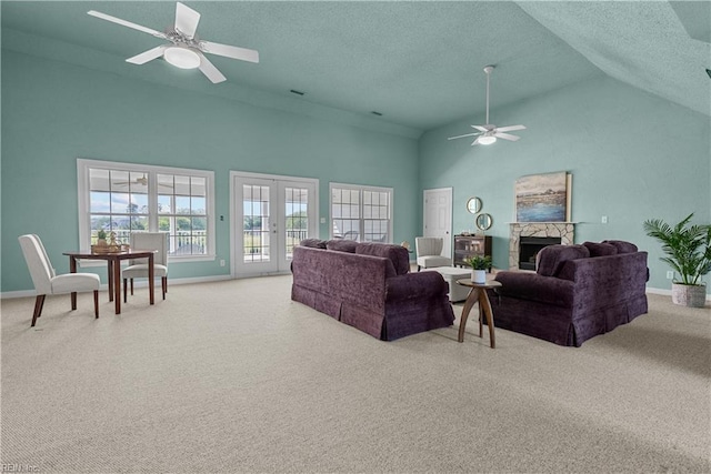 carpeted living area featuring a ceiling fan, a textured ceiling, a fireplace, baseboards, and high vaulted ceiling