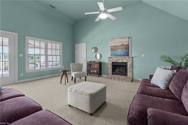 carpeted living room featuring ceiling fan, a stone fireplace, visible vents, baseboards, and high vaulted ceiling