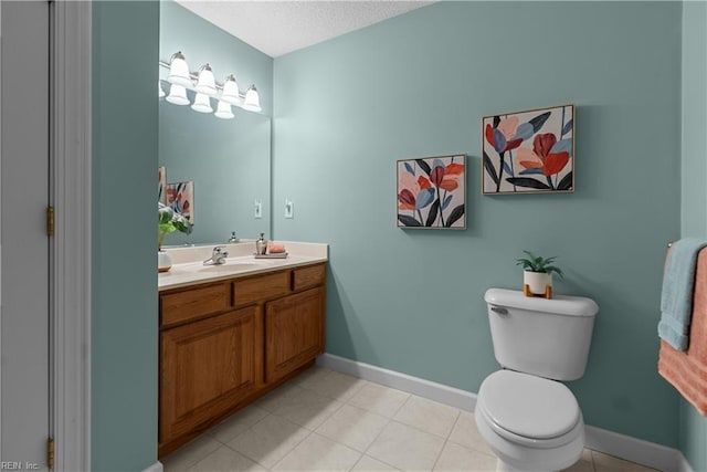bathroom featuring tile patterned flooring, vanity, toilet, a textured ceiling, and baseboards
