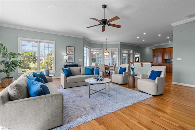 living area with crown molding, ceiling fan, recessed lighting, baseboards, and light wood-type flooring