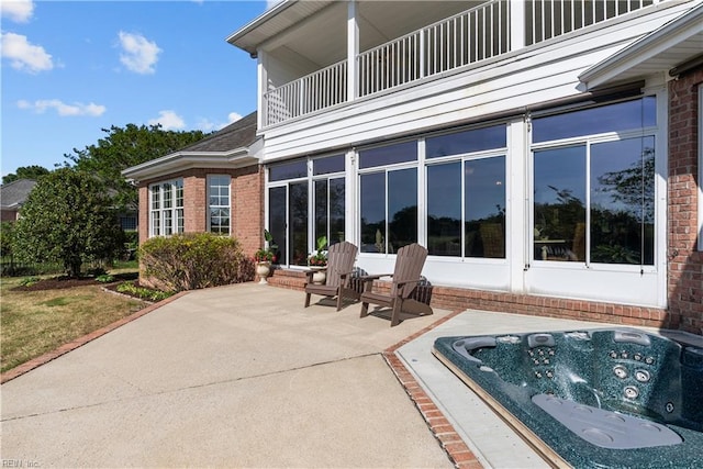 view of patio / terrace featuring an outdoor hot tub and a balcony