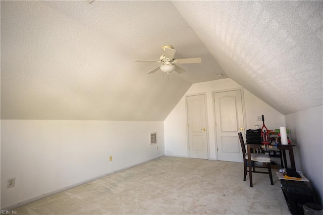 bonus room with lofted ceiling, a textured ceiling, ceiling fan, visible vents, and light carpet