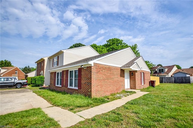 view of front of house featuring a front lawn, fence, and brick siding