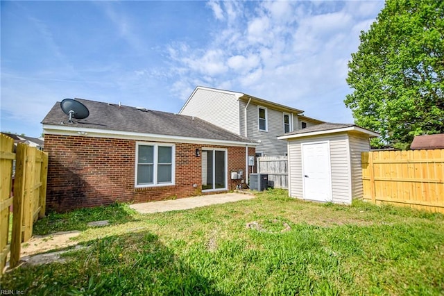 back of property with a storage unit, a fenced backyard, and a yard