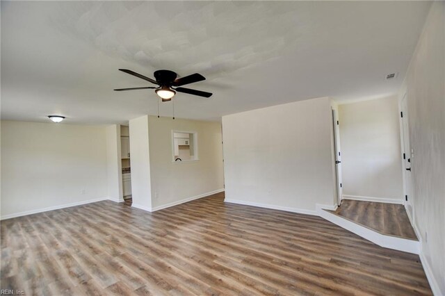 spare room featuring baseboards, visible vents, wood finished floors, and a ceiling fan