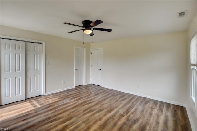 unfurnished bedroom with visible vents, a closet, baseboards, wood finished floors, and a ceiling fan