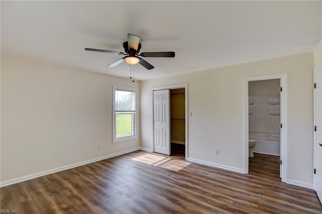 unfurnished bedroom featuring dark wood-style flooring, a closet, and baseboards
