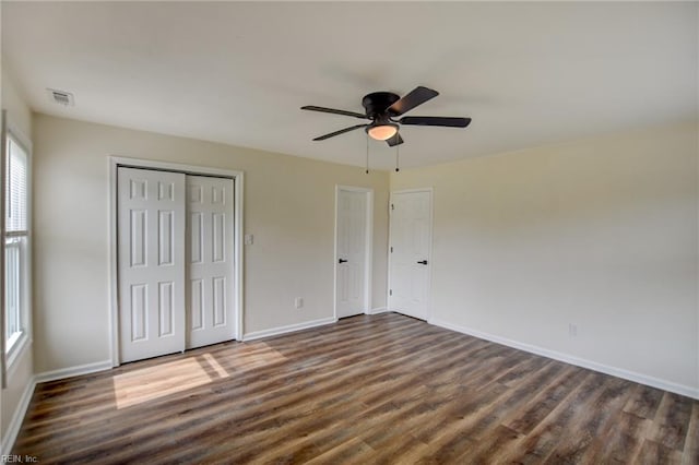 unfurnished bedroom with baseboards, a ceiling fan, a closet, and dark wood-type flooring
