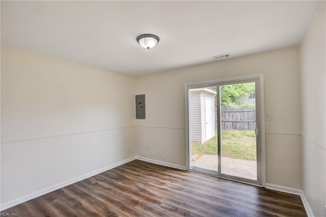 spare room with electric panel, baseboards, dark wood-style flooring, and visible vents