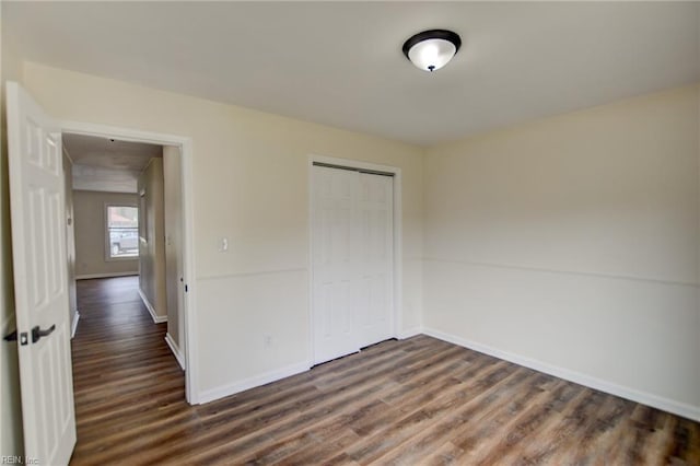 unfurnished bedroom featuring a closet, baseboards, and dark wood finished floors