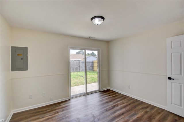spare room featuring dark wood-style flooring, visible vents, electric panel, and baseboards