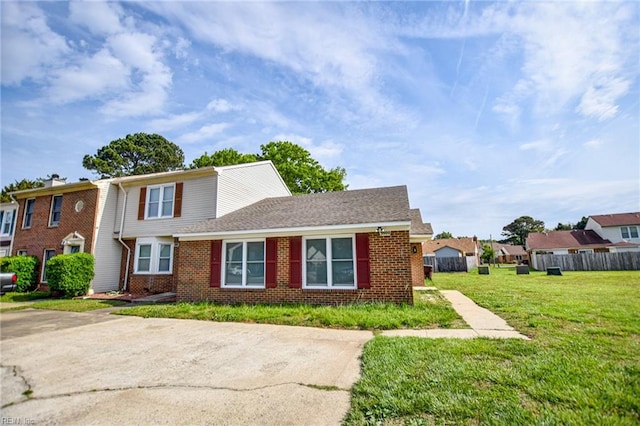 view of front of home with a front lawn, fence, and brick siding